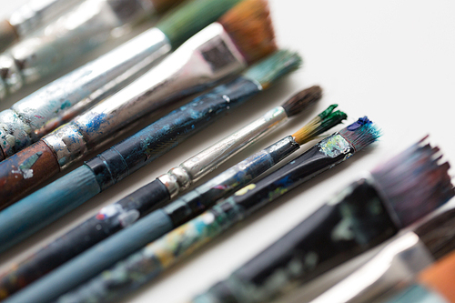 fine art, painting, creativity and artistic tools concept - close up of dirty paintbrushes