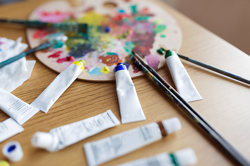 fine art, creativity and artistic tools concept - palette, brushes and paint tubes on table