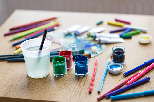 fine art, creativity and artistic tools concept - gouache colors, felt tip pens and pencils on table