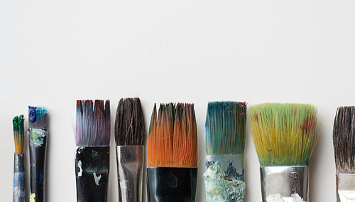 fine art, painting, creativity and artistic tools concept - dirty paintbrushes from top