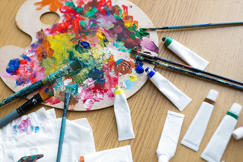 fine art, creativity and artistic tools concept - close up of palette, brushes and paint tubes on table
