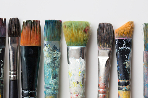 fine art, painting, creativity and artistic tools concept - close up of dirty paintbrushes from top