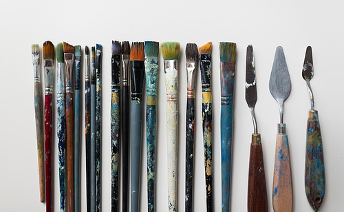 fine art, creativity and artistic tools concept - palette knives or painting spatulas and paintbrushes from top
