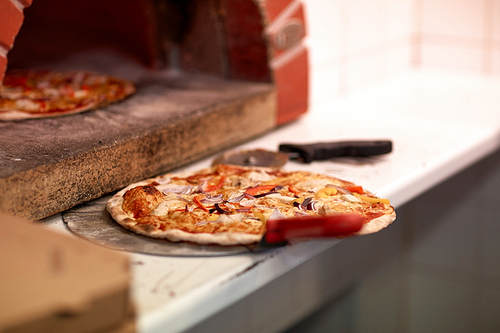 food, italian kitchen, culinary and cooking concept - baked pizza on peel and oven at pizzeria