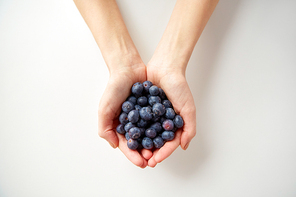healthy eating, vegetarian food and people concept - close up of young woman hands holding blueberries