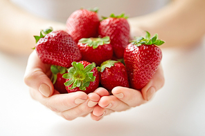 healthy eating, vegetarian food and people concept - close up of young woman hands holding strawberries