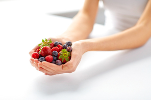 healthy eating, vegetarian food and people concept - close up of young woman hands holding berries