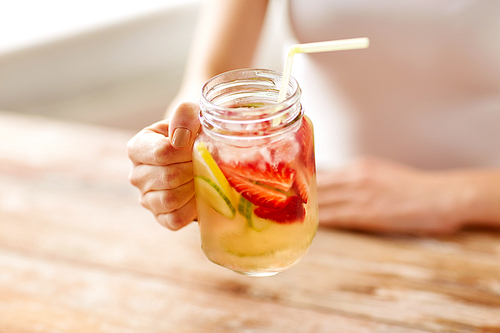 healthy eating, detox and people concept - close up of woman holding mason jar glass with fruit water at home