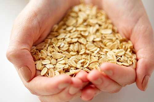 food, healthy eating and people concept - close up of hands holding oat flakes