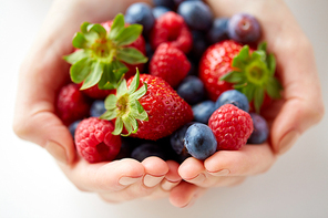 healthy eating, vegetarian food and people concept - close up of young woman hands holding berries