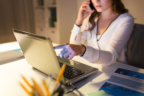 business, technology, overwork, deadline and people concept - woman with laptop calling on smartphone at night office