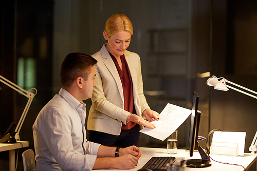 business, deadline and technology concept - coworkers with papers working late at night office