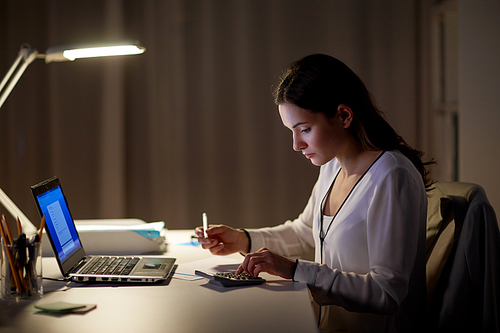 business, accounting, overwork, deadline and people concept - woman with tax form and calculator working at night office