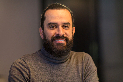 portrait and people concept - smiling middle eastern man with beard in polo neck sweater