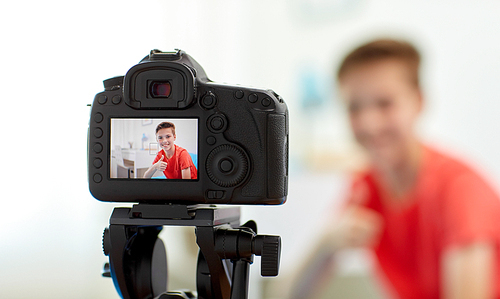 blogging, technology and people concept - camera recording video of happy smiling . boy showing thumbs up at home