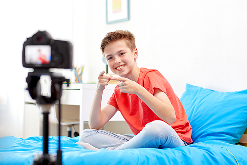 blogging, technology and people concept - happy smiling boy or . with camera recording video at home