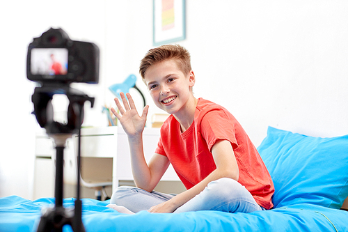 blogging, technology and people concept - happy smiling boy or . with camera recording video at home