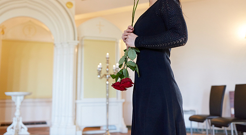 burial, people and mourning concept - sad woman with red rose at funeral in orthodox church