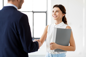 business people, partnership and cooperation concept - happy smiling businesswoman with folder and businessman shake hands at office