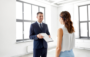 real estate business, sale and people concept - male realtor with clipboard showing contract document to customer at new office room