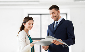 real estate business, sale and people concept - happy smiling realtor with folder showing documents to female customer at new office room