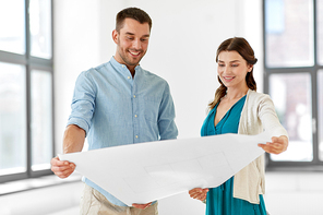 mortgage, people and real estate concept - happy couple with blueprint at to new home