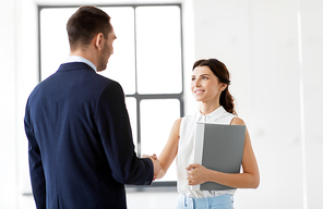 business people, partnership and cooperation concept - happy smiling businesswoman with folder and businessman shake hands at office