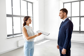 real estate business, sale and people concept - male realtor with clipboard showing contract document to customer at new office room