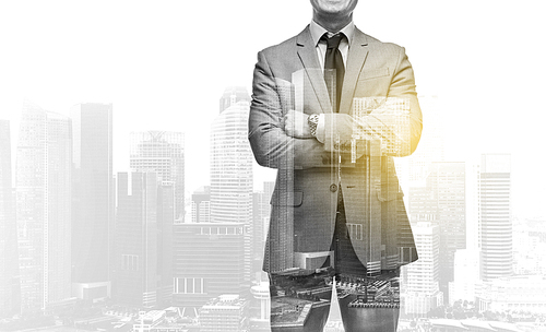 business, people and corporate concept - handsome businessman with crossed arms over over city skyscrapers background and double exposure effect