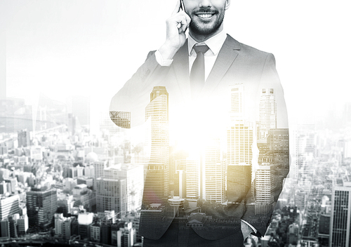 business, technology and people concept - close up of smiling businessman calling on smartphone over city buildings and double exposure effect