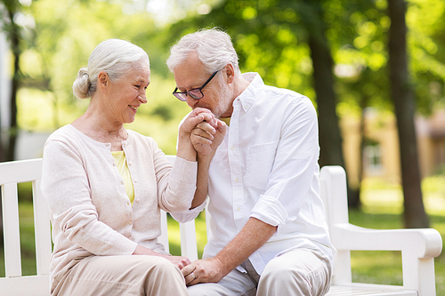 old age, relationship and people concept - happy senior couple sitting on bench at summer park