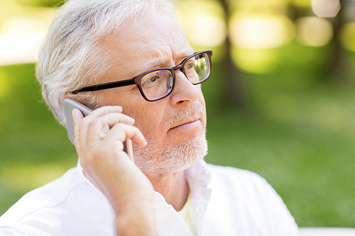 technology, senior people, and communication concept - close up of sad old man in glasses calling on smartphone at summer park