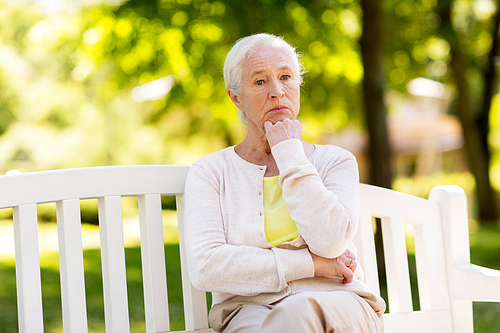 old age, retirement and people concept - sad senior woman sitting on bench at summer park