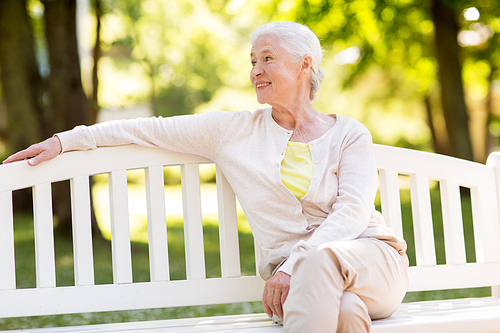 old age, retirement and people concept - happy senior woman sitting on bench at summer park