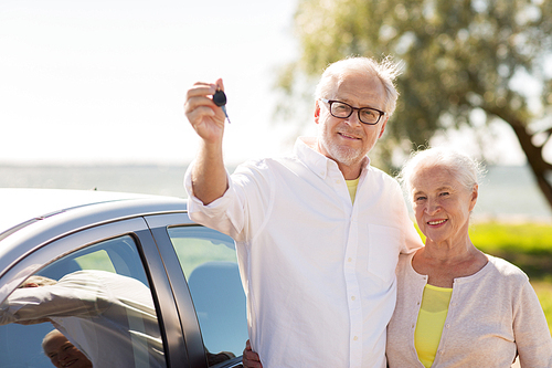 road trip, travel and old people concept - happy senior couple with car key at seaside