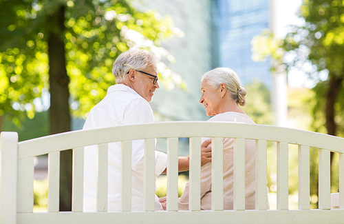 old age, relationship and people concept - happy senior couple sitting on bench at summer park