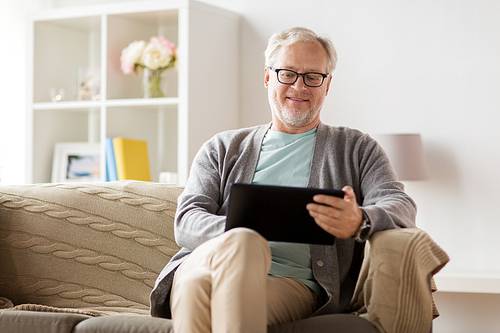 technology, old age, people and lifestyle concept - happy smiling senior man with tablet pc computer sitting on sofa at home