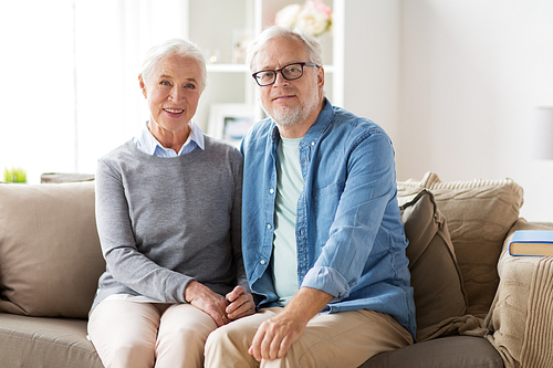 relationships, old age and people concept - happy senior couple sitting on sofa at home
