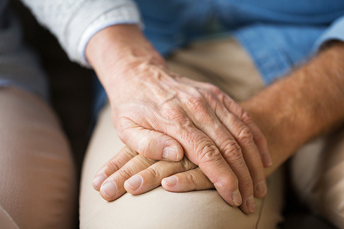 relationships, charity, old age and people concept - close up of senior couple holding hands