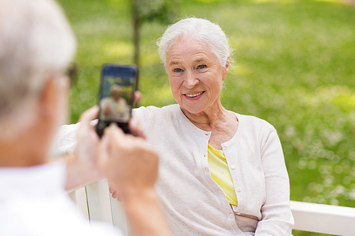 technology, retirement and old people concept - happy smiling senior couple with smartphone photographing in summer park