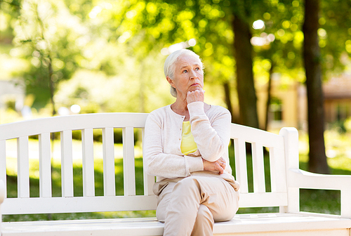 old age, retirement and people concept - sad senior woman sitting on bench at summer park