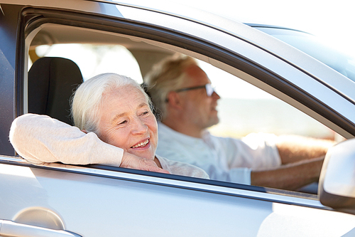road trip, travel and old people concept - happy senior couple driving in car