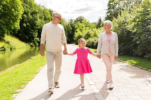 family, generation and people concept - happy smiling grandmother, grandfather and little granddaughter walking at park