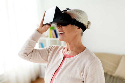 technology, augmented reality, entertainment and people concept - senior woman with virtual headset or 3d glasses playing videogame at home