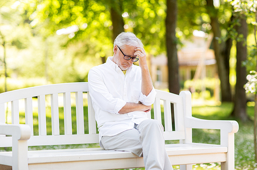 old age, retirement and people concept - thoughtful senior man in glasses sitting on bench at summer park