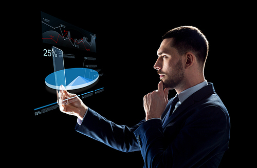 business, augmented reality and future technology concept - businessman in suit working with transparent tablet pc computer and virtual charts projections over black background