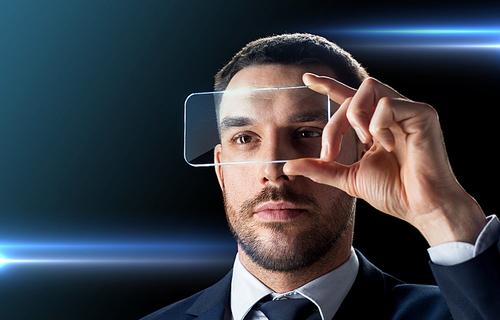business, augmented reality and future technology concept - businessman in suit working with transparent smartphone over black background