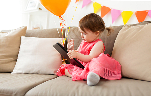 childhood, people and celebration concept - happy baby girl with tablet pc computer on birthday party at home
