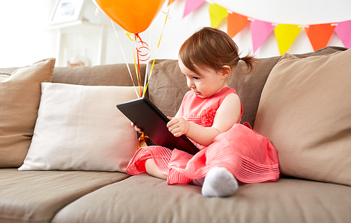 childhood, holidays and people concept - happy baby girl with tablet pc computer and air balloons on birthday party at home