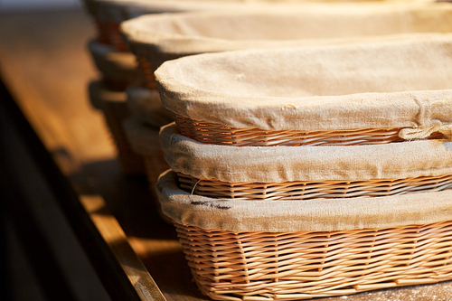 food, cooking and baking concept - bakery wicker baskets on wooden kitchen table